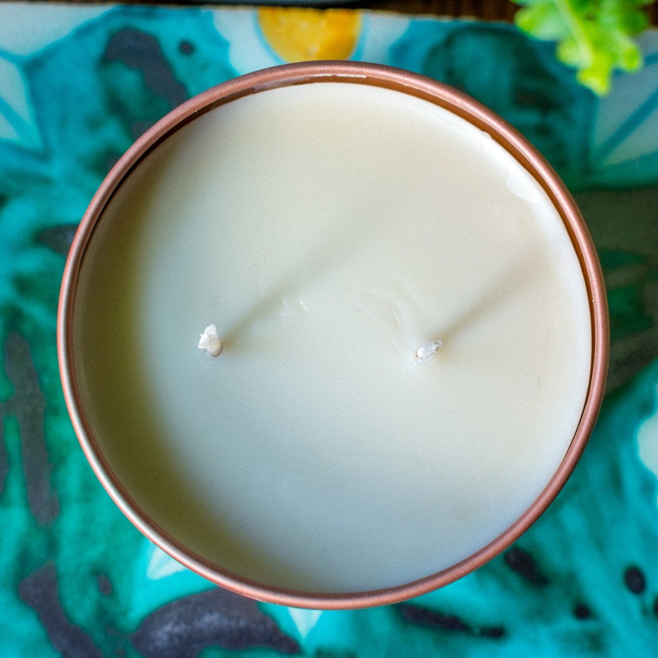 An overhead image shows the top view of a Croft & Wylde container candle in a rose gold tin with two wicks and cream coloured wax.